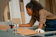 © narong - Professional carpenter woman check about cutting machine during work with wood product in workplace.