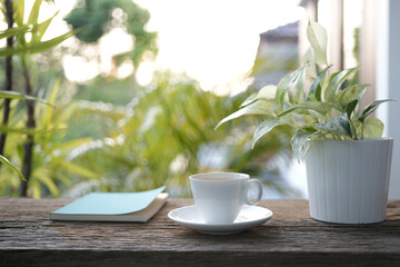 Wall Mural - Blue notebook and wooden coffee cup and pothos plant pot on wooden table with greenery scene