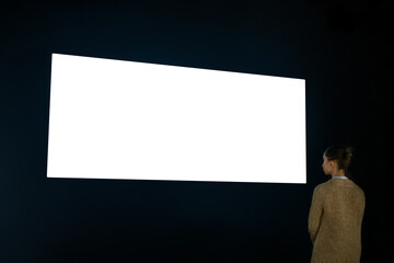 woman looking at wide large wall blank interactive white display in dark room of modern technology e