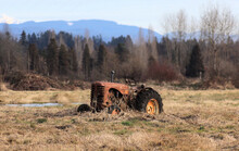 Lonely Tractor Abandoned In The Grassy Autumn Field