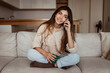 © Prostock-studio - Positive millennial european female calling by smartphone, talking, sit at sofa in light living room interior