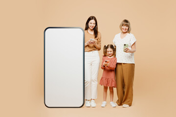 Wall Mural - Full body women wear casual clothes with child kid girl 6-7 years old. Granny mother daughter big huge blank screen use mobile cell phone isolated on plain beige background. Family parent day concept.