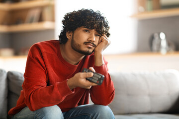 Poster - Portrait Of Bored Upset Young Indian Guy Watching TV At Home