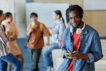 Wall Mural - Portrait of African American student smiling at camera while standing in lecture hall with his classmates in background