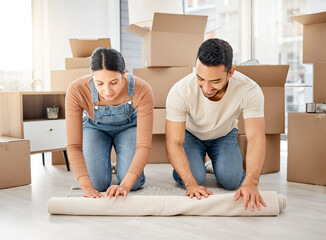 Aufkleber - Theyre slowly starting to make this place theirs. Shot of a young couple rolling out a carpet together in their new home.