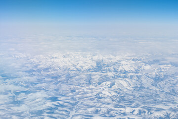 Wall Mural - Aerial view of the Siberian hills and mountains covered with snow in the tundra. Siberia, Far East of Russia. Snow-covered tundra in the Arctic.