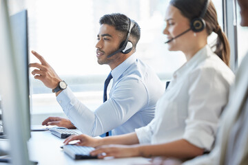 Poster - Probably the most competent call centre staff youll ever dealt with. Shot of a man pointing at his computer while wearing a headset in a call center.