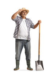 Sticker - Full length portrait of a happy mature farmer with a shovel greeting with hat