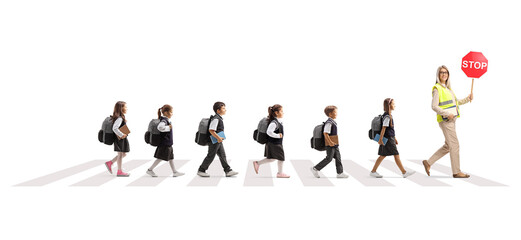 Canvas Print - Full length profile shot of a teacher with stop sign and schoolchildren crossing road at a pedestrian crossing