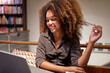 portrait young black afro young woman looking using her laptop smiling grabbing her hair in a cafe or library