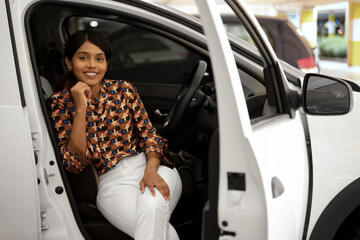 Beautiful Indian woman sitting inside in car looking at camera. Transportation concept