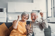 © Daniel - Happy older couple sit on couch staring at cellphone screen gesturing looking overjoyed, scream with joy, read fantastic news, get great commercial offer, pension raise. Success, achievement concept.