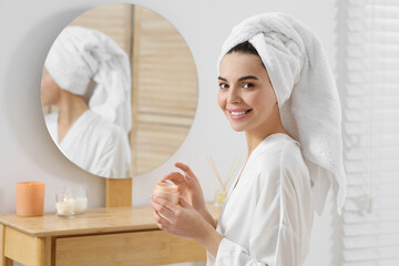 Wall Mural - Beautiful happy woman in stylish bathrobe with cream in bathroom