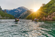 © .shock - A group of friends enjoying fun and kayaking exploring the calm river, surrounding forest and large natural river canyons during an idyllic sunset.