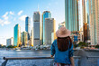 beautiful long hair woman in a hat watching the sunset over brisbane city; city reach boardwalk with amazing view of large skyscrapers by brisbane river, australia, holidays in brisbane