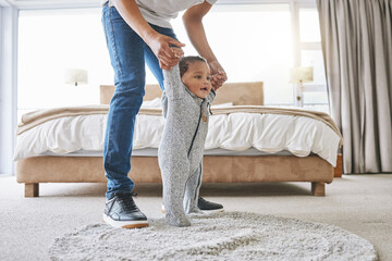 Wall Mural - Tiny steps from tiny feet. Shot of a young father holing his adorable young baby at home.