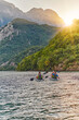 © .shock - A group of friends enjoying fun and kayaking exploring the calm river, surrounding forest and large natural river canyons during an idyllic sunset.