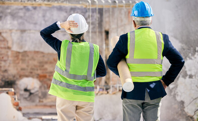 It always seems impossible until its done. Shot of engineers standing with blueprints on a construction site.