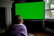 © Oleksandra - Back View of the Happily Married Black Couple Eating Popcorn on the Sofa and Watching TV with Green Screen Mock Up Display in Loft Living Room. Out of Focus Couple Close Up Shot