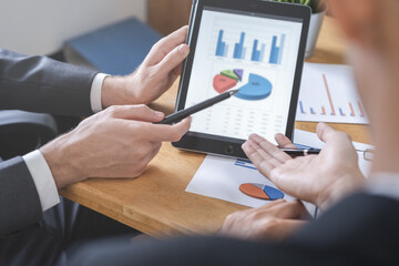 Business meeting, two caucasian, asian group man use tablet brainstorm analyzing on graph data of cost plan or document, paperwork and discussing in board room on table. People working conference room