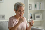 Fototapeta Mapy - Asian senior woman taking medicine at home, age, medicine, healthcare and people concept