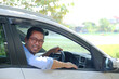 © KrishnaTedjo - Asian man looking from inside his car with happy expression