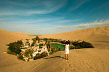 Woman Crossing The Huacachina Oasis, In The Desert Sand Dunes Near The City Of Ica, Peru