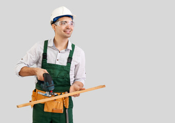 Wall Mural - young carpenter sawing wooden plank on grey background