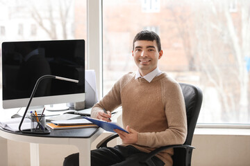 Wall Mural - Young accountant with document sitting at table in office