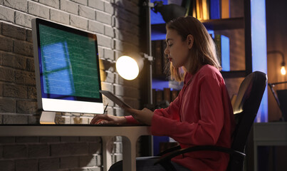 Female programmer working with tablet computer in office at night