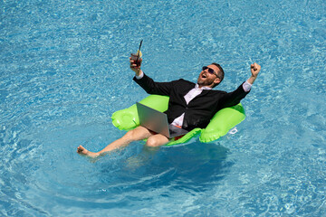 Crazy summer. Business drink summer cocktail and using laptop in suit in water pool. Fun business lifestyle. Funny businessman dreams about summer. Freelance concept, summer travel. Business success.