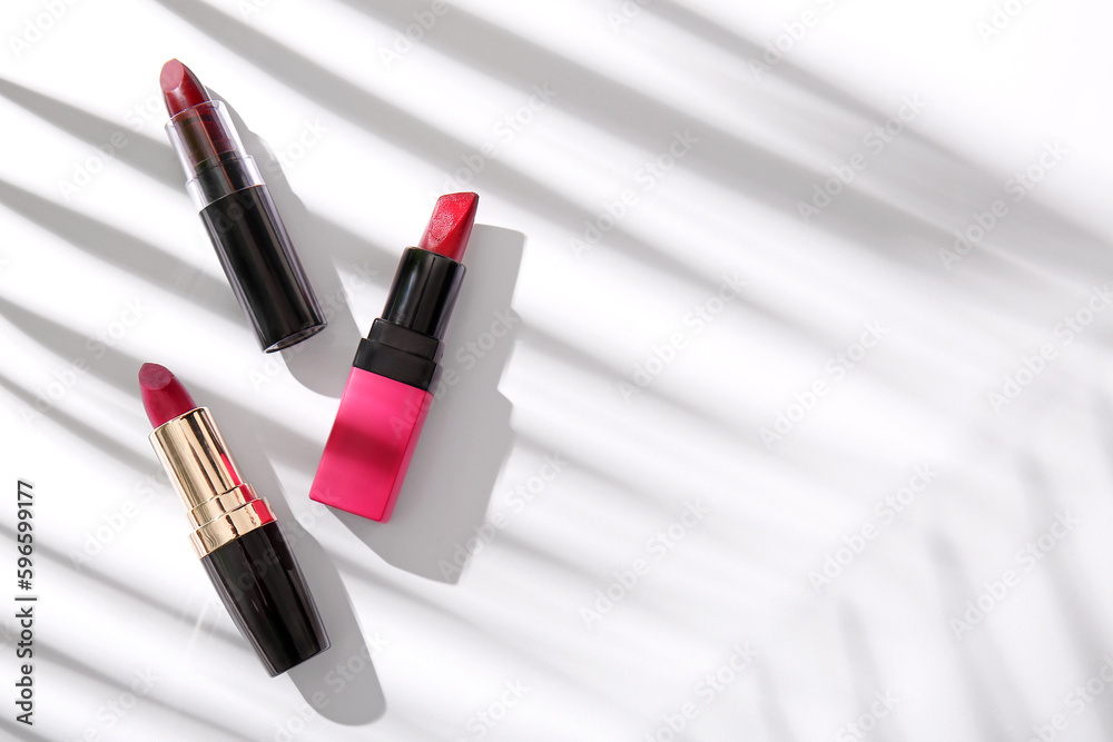 Set of beautiful lipsticks and shadows on light background