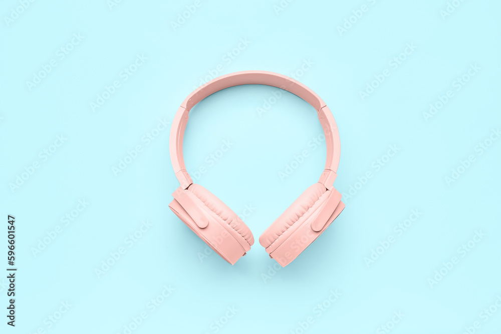 Modern pink headphones on blue background