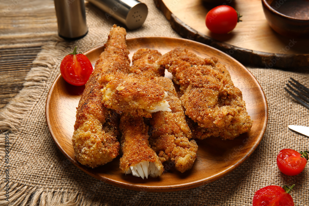 Plate of tasty fried codfish on wooden background