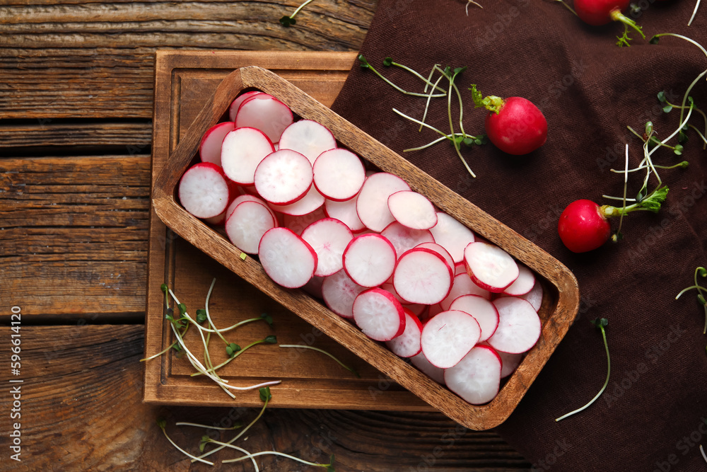Board with slices of fresh radish on wooden table