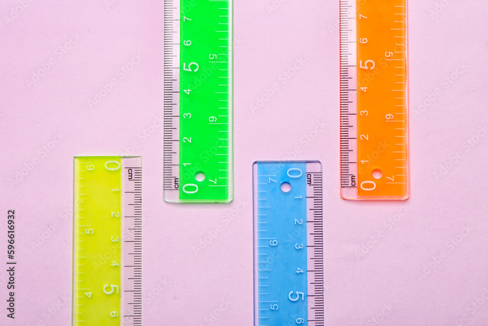 Colorful plastic rulers on pink background