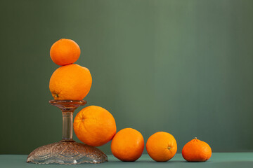 Wall Mural - oranges with vintage glass vase on green background