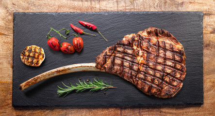 Poster - Grilled  delicious  tomahawk steak and some seasonings on black slate serving plate. Flat lay.