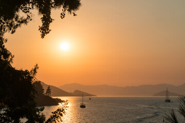 Wall Mural - calm sea and sunset. sun is setting behind the hills on the horizont. beautiful nature background.