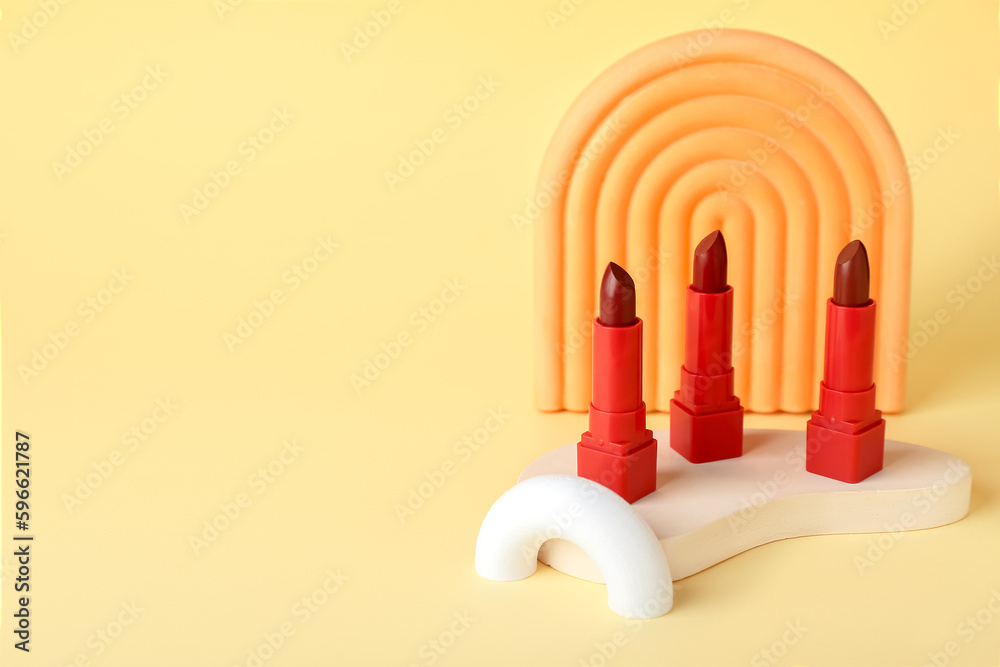 Decorative plaster podiums and lipsticks on yellow background
