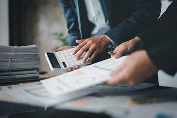 Accountant checking financial statement or counting by calculator income for tax form, Business woman sitting and working with colleague discussing the desk in office. Audit concept