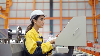 Young woman technician worker in uniform checking and repair system manufacturing control machine at industry factory