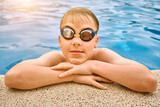 Fototapeta  - Smiling boy portrait in swimming goggles, Child swim in the pool, sunbathes, swimming in hot summer day. Sport, Travel, Holidays

