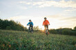 © Andrii IURLOV - Mother and son ride a bike. Happy cute boy in helmet riding a bike in park on green meadow at sunset time. Family weekend.