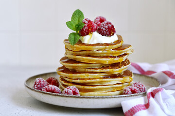 Wall Mural - Delicious homemade pancakes with whipped cream, maple syrup and raspberry for a breakfast.