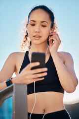 Canvas Print - Lining up her playlist. Cropped shot of an attractive young female athlete listening to music while out for a run in the city.