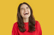 © Studio Romantic - Studio shot of happy laughing woman. Pretty young girl in red sweatshirt standing isolated on bright yellow background and laughing happily at very funny joke. Laughter, emotion concept