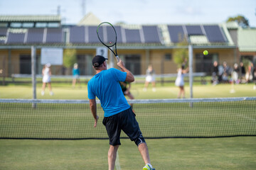 Wall Mural - Amateur playing tennis at a tournament and match on grass in Europe 