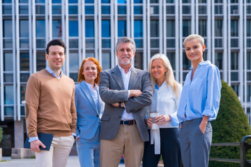 Portrait of cheerful group of coworkers walking outdoors in a corporate office area