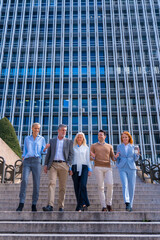 Cheerful group of coworkers outdoors in a corporate office area going down some stairs going to work, businesswoman and businessman